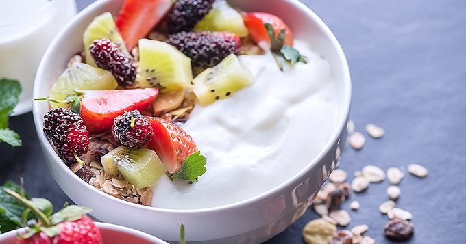 A bowl of frozen yogurt with grain and fruit toppings | Trainest 