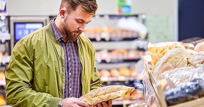 Someone holding a pack of whole-grain bread inside a grocery | Trainest 