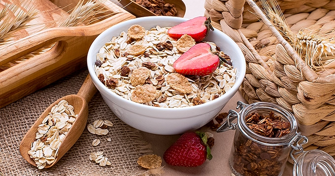 A bowl of oatmeal topped with strawberries and nuts | Trainest 