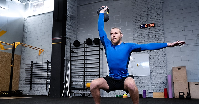 A man doing a kettlebell single-arm overhead squat | Trainest
