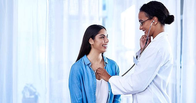 A doctor examining her patient with a stethoscope | Trainest 