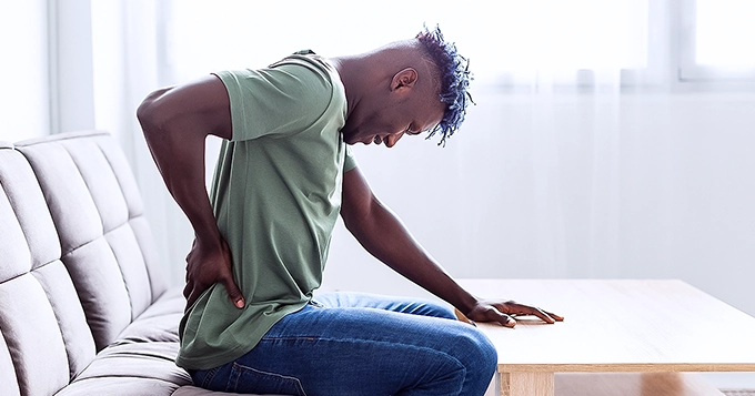 A man holding his lower back in pain | Trainest 