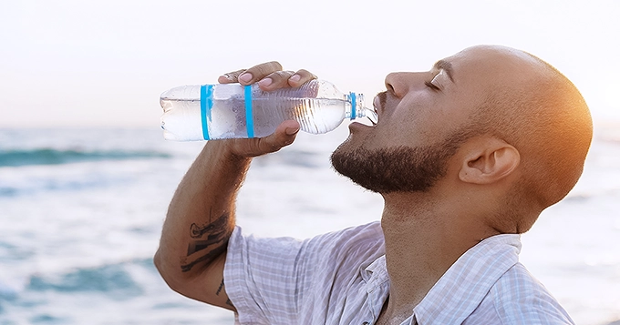 A man at the beach taking a big gulp of water | Trainest