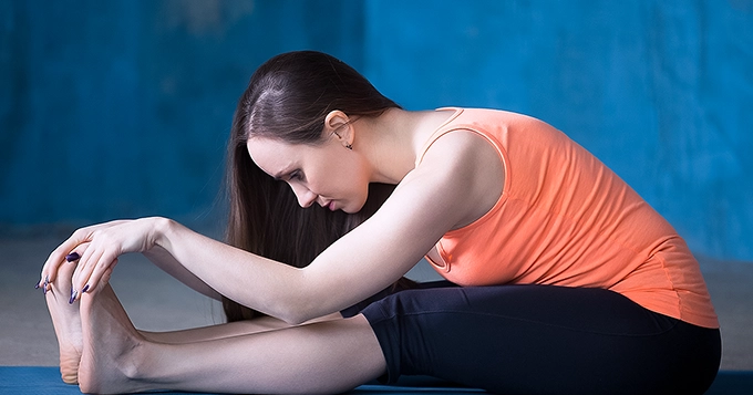 A woman holding a seated hamstring stretch | Trainest 