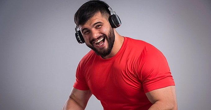 A muscular man wearing headphones | Trainest 