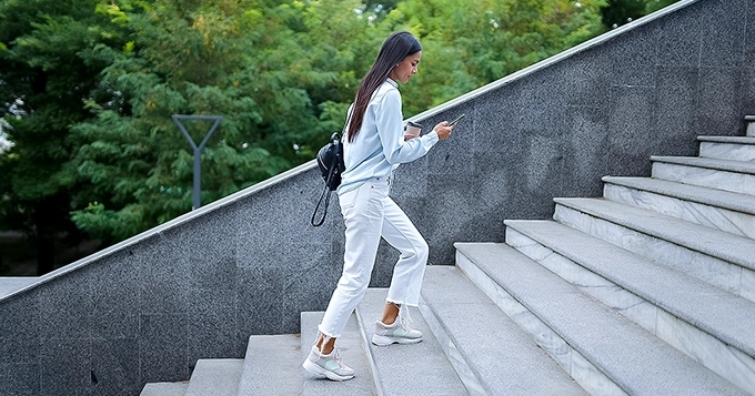 A casually-dressed woman walking up a staircase | Trainest 