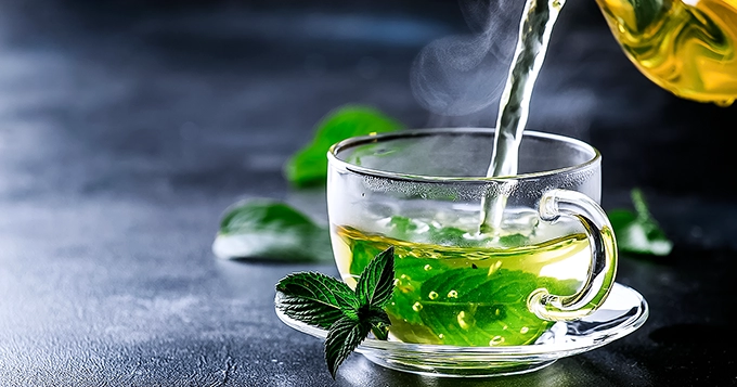 Green tea being poured from a pot to a cup | Trainest 