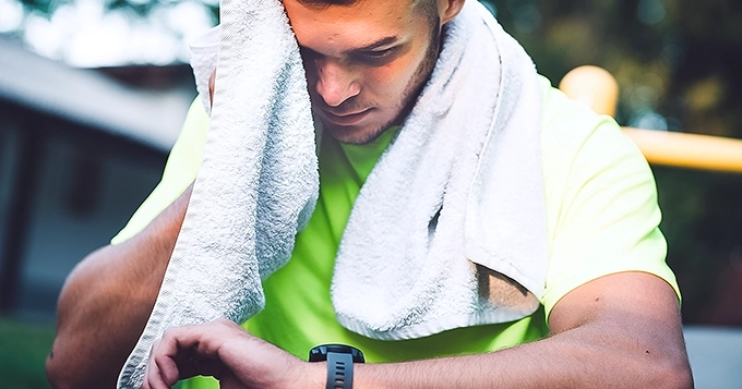 A man who just finished working out looking at his smartwatch | Trainest
