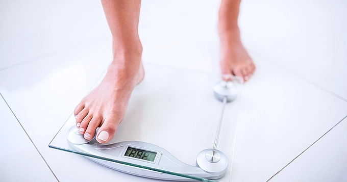 Someone stepping onto a digital scale | Trainest
