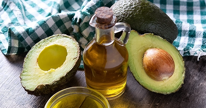 Sliced avocados and a bottle of avocado oil | Trainest
