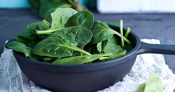 A pan of uncooked spinach | Trainest 