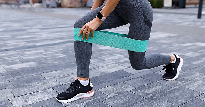 A lady doing lunges with a resistance band around her legs | Trainest 