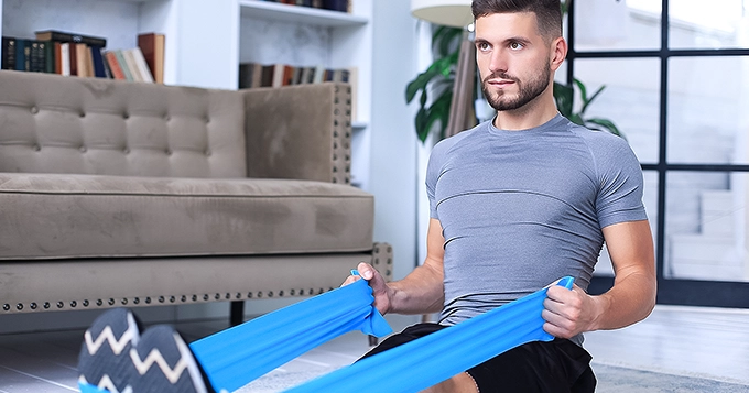 A man doing seated resistance band rows at home | Trainest 