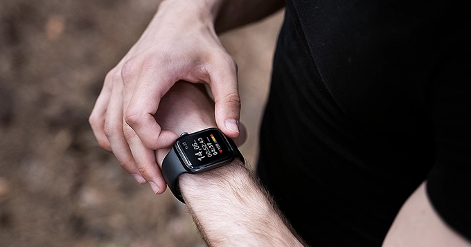 Someone walking while using a smartwatch to track exercise metrics | Trainest 