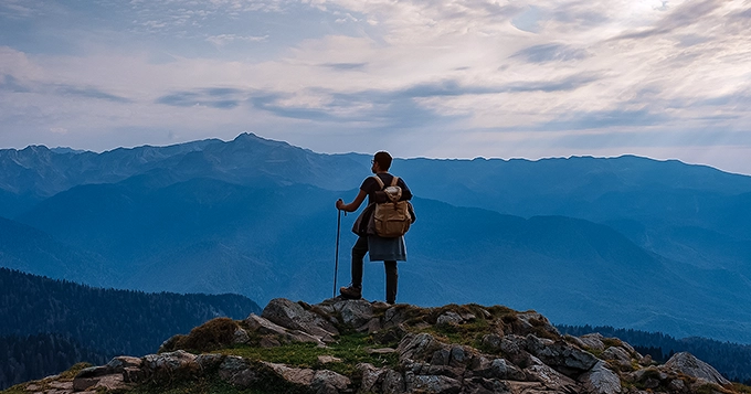 A hiker enjoying the view on top of a mountain | Trainest 