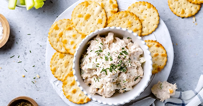 A bowl of tuna salad with a plate of crackers | Trainest 