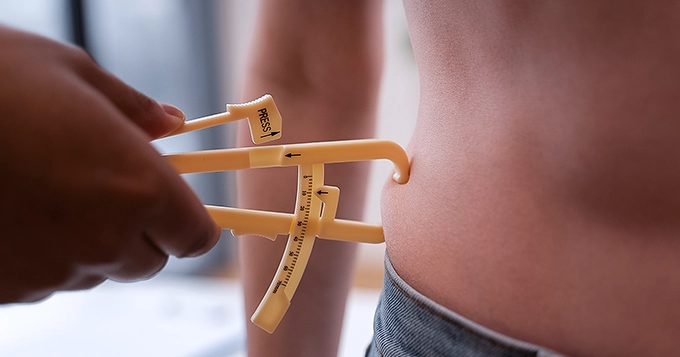 Someone getting their body fat measured with a skinfold caliper | Trainest
