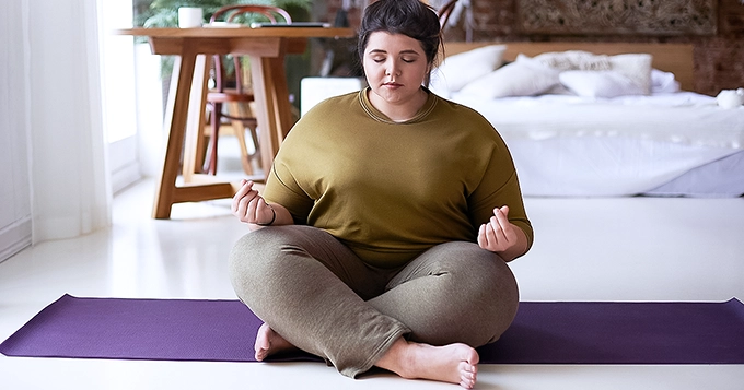 A woman meditating in the bedroom | Trainest
