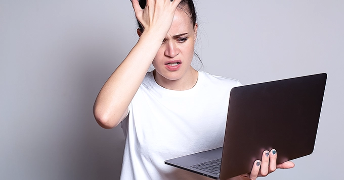 A frustrated woman holding a laptop | Trainest 