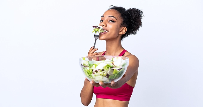 A fit girl eating a healthy bowl of vegetables | Trainest 