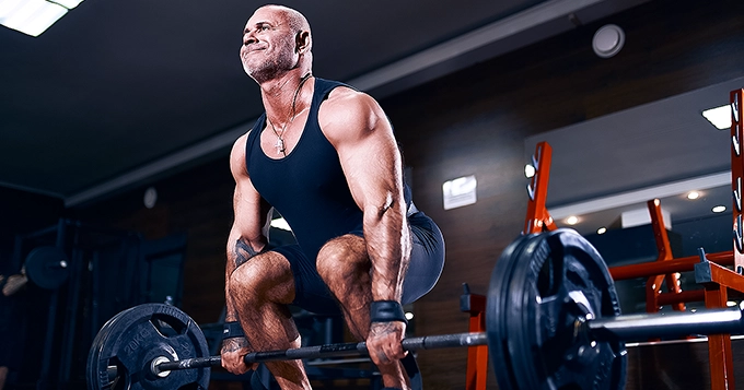 A muscular man doing heavy barbell deadlifts | Trainest
