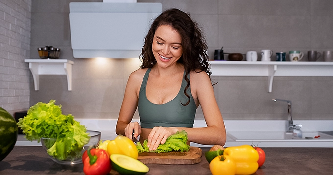 A fit girl preparing a healthy meal in the kitchen | Trainest
