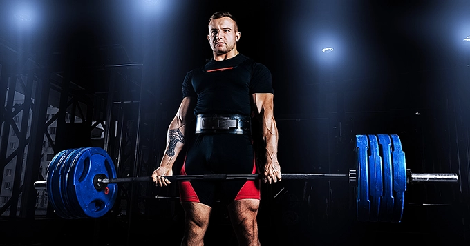 A powerlifter wearing a lifting belt while deadlifting | Trainest 