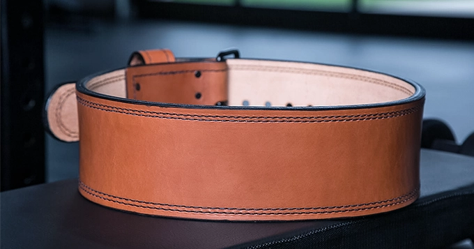 A leather lifting belt on a gym bench | Trainest 