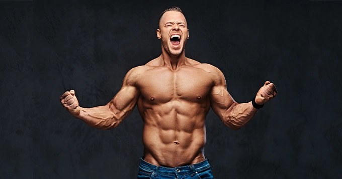 A muscular man flexing his abs and arms | Trainest 