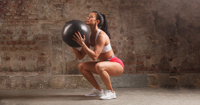 A fit woman doing Bosu ball squats | Trainest 