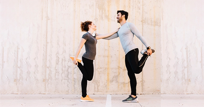 A couple doing a balance exercise together | Trainest 