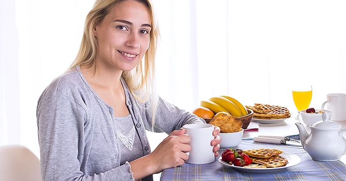 A woman eating a hearty breakfast | Trainest 