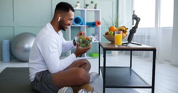 A man in workout clothes eating a bowl of salad | Trainest 