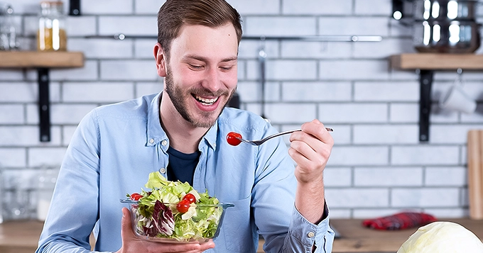 A man eating a bowl of fresh salad | Trainest 