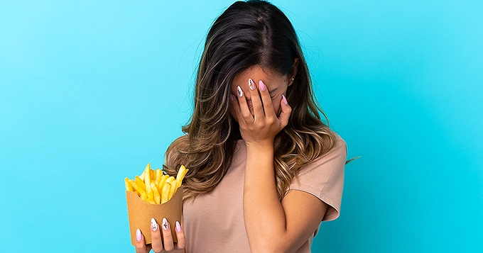 Someone feeling guilty about eating unhealthy food | Trainest 