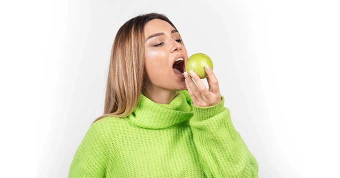 A woman taking a bite out of an apple | Trainest 