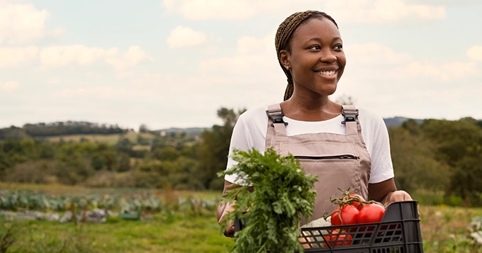 A farmer holding a basket of freshly harvested vegetables | Trainest 