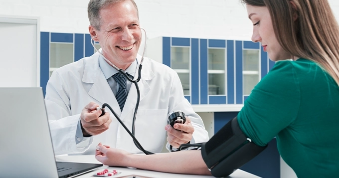 Someone getting her blood pressure checked by a doctor | Trainest
