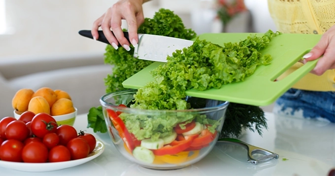 A woman preparing a bowl of salad | Trainest
