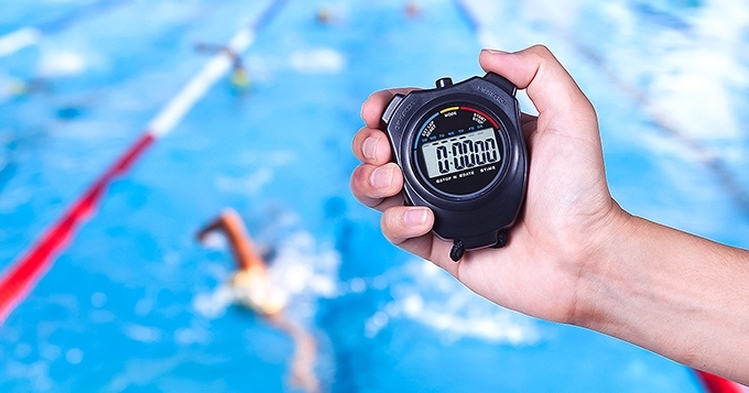 Someone using a stopwatch at a swim event | Trainest 