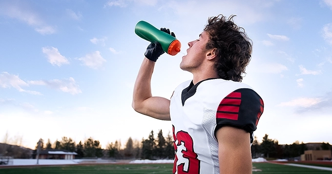 A footballer hydrating himself during a game | Trainest 