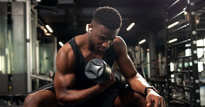 A man doing concentration curls in a gym | Trainest 