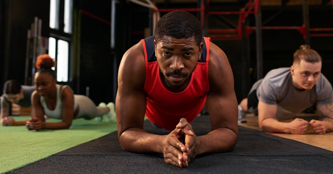 A group of exercisers doing planks | Trainest 