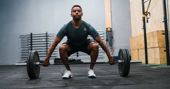 A man pulling a barbell from the floor with a snatch grip | Trainest 