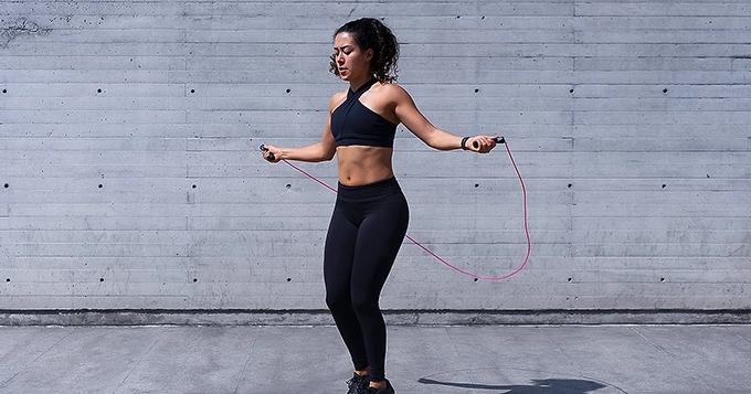 A woman doing outdoor cardio using a jump rope | Trainest
