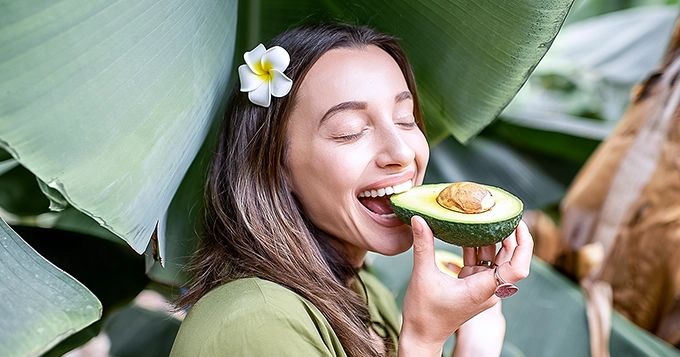 A woman eating an avocado | Trainest 