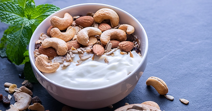 A bowl of yogurt topped with a variety of nuts | Trainest 