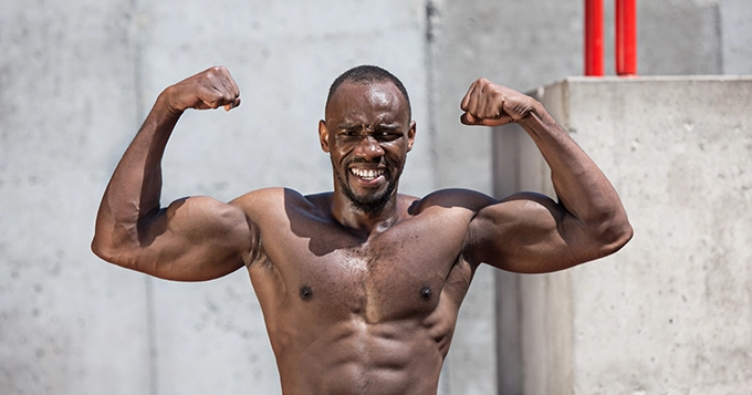 A muscular man doing a front double bicep pose | Trainest 