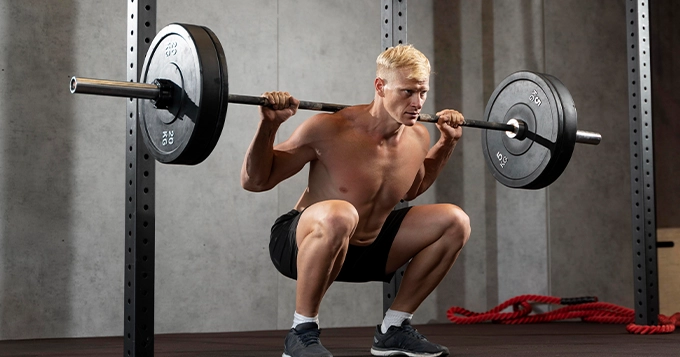 A man back-squatting with a heavy barbell | Trainest 