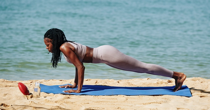 A woman doing Yoga at the beach | Trainest 